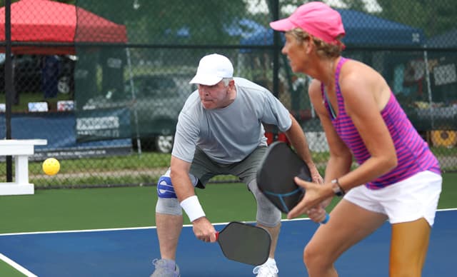 Active adult couple playing pickle ball at Kings Point